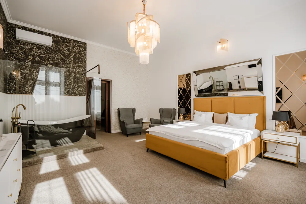 Dormitorul Apartamentului Deluxe, cu pat matrimonial tapițat și candelabru de cristal