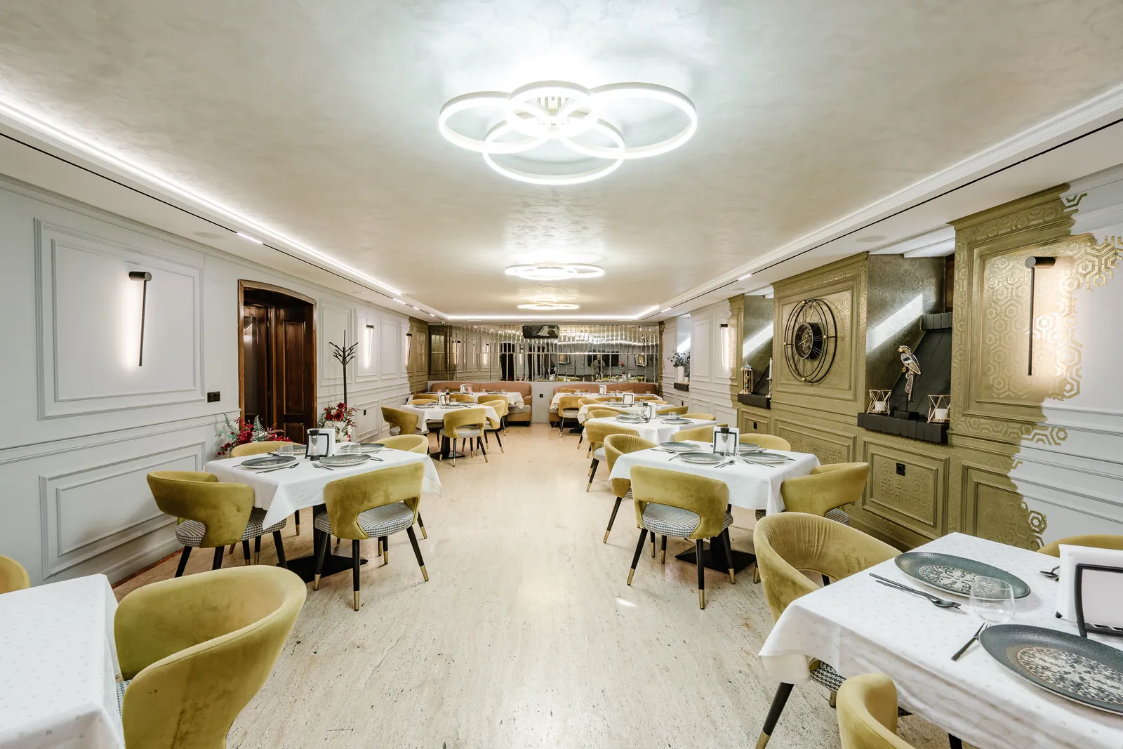 Sala restaurantului La Maison de Caroline, cu mese aranjate și scaune din catifea aurie