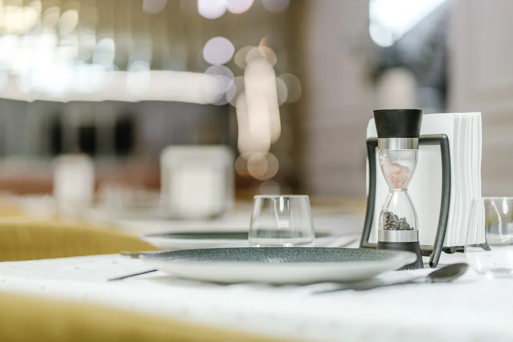Detaliu de masă în restaurant, cu clepsidră decorativă și pahare